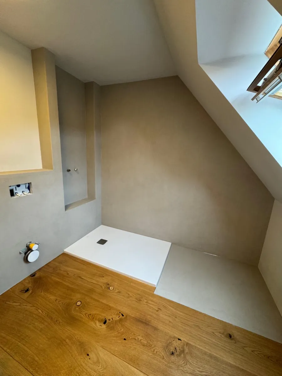 Fugenloses Bad mit Dusche unter der Dachschräge und Holzboden