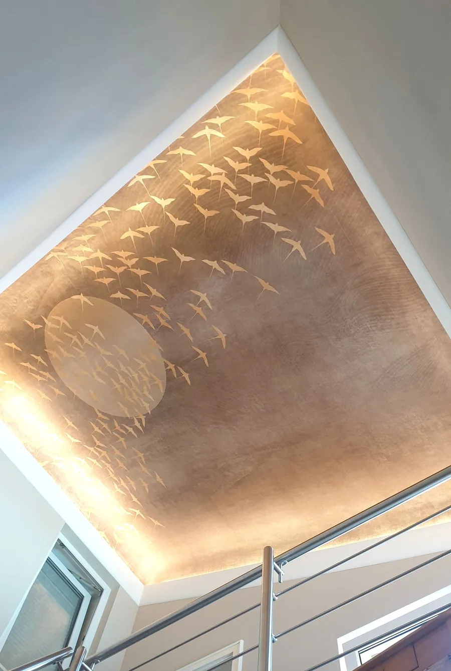 Decke mit goldenem Vogel-Relief und indirekter Beleuchtung